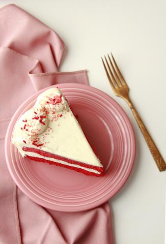 Slice of streamlined red velvet cake on a pink plate with fork